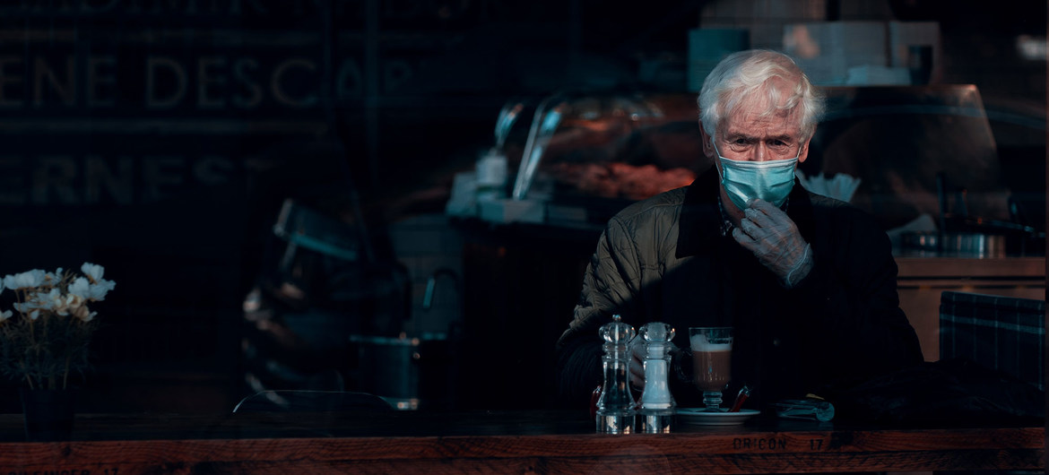 A man wears a face mask and gloves while sitting in a cafe in Glasgow, Scotland.